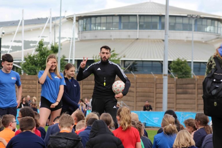Football freestyler teaching freestyle skills to kids at a football workshop